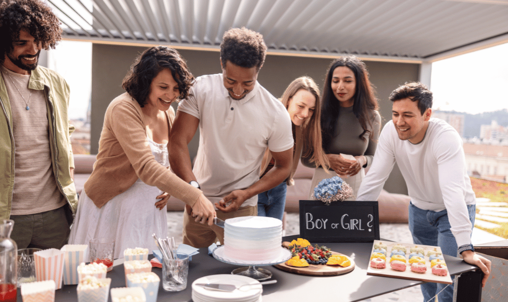 people at a gender reveal party cutting a cake.